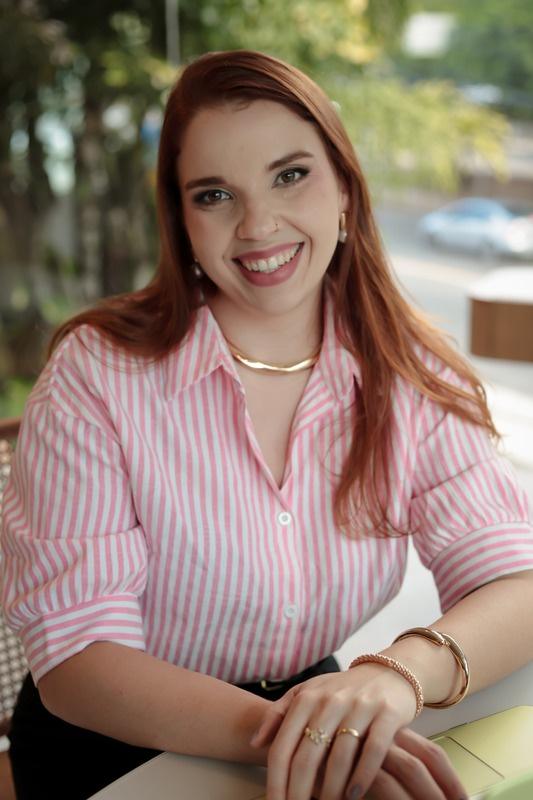 Bruna sorrindo, de camisa listrada rosa